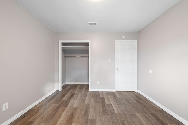 unfurnished bedroom with dark hardwood / wood-style flooring and a closet