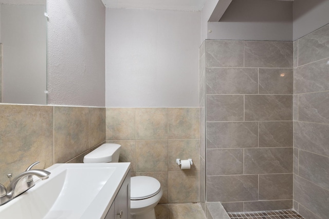 bathroom featuring vanity, tiled shower, tile walls, and toilet