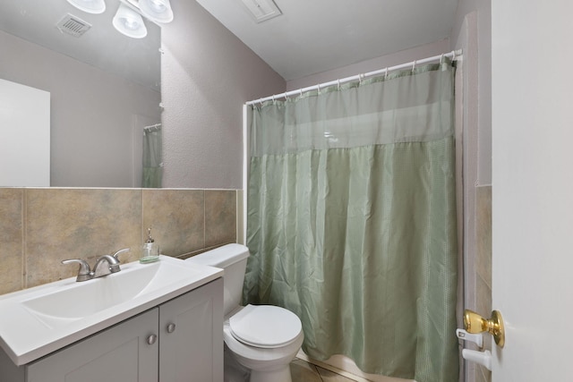 bathroom featuring walk in shower, vanity, toilet, and tile walls