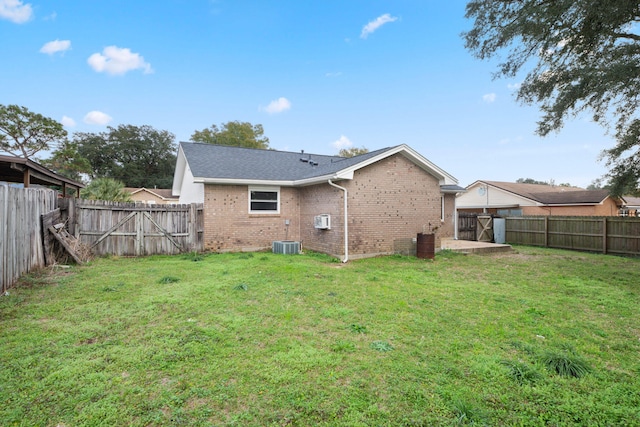 rear view of property featuring central AC and a lawn