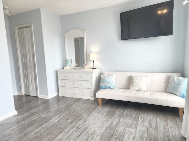 interior space with baseboards, a textured ceiling, and wood finished floors