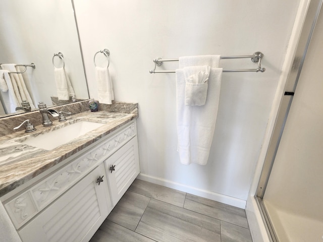 bathroom with tile patterned floors, baseboards, vanity, and a shower stall