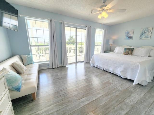 bedroom featuring a textured ceiling, light wood-style floors, ceiling fan, and access to outside