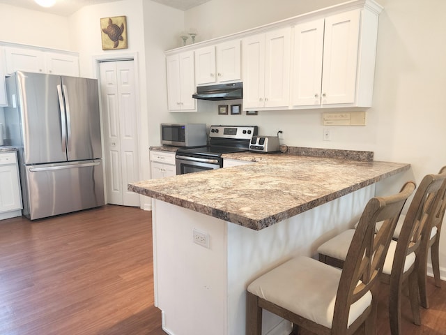 kitchen featuring white cabinetry, appliances with stainless steel finishes, and a kitchen breakfast bar