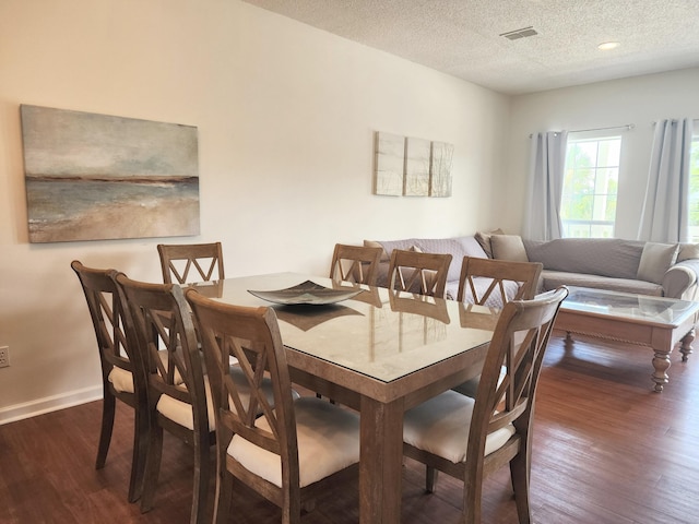 dining area with visible vents, baseboards, a textured ceiling, and wood finished floors