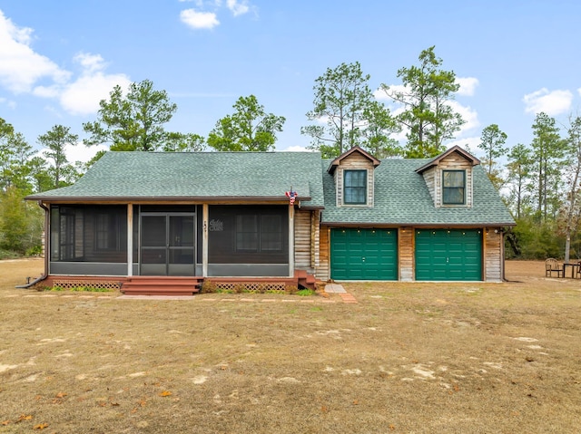 view of front of house featuring a garage, a front lawn, and a sunroom