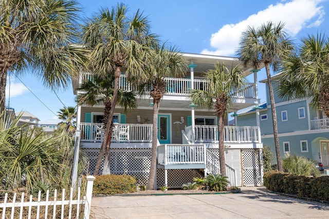 coastal inspired home featuring a balcony, stairs, and a porch