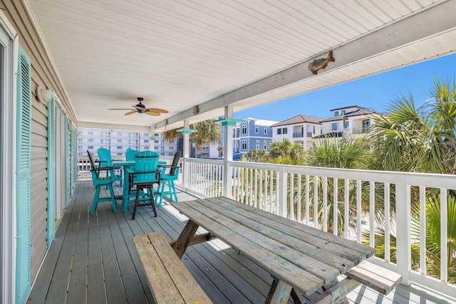 wooden terrace with ceiling fan, outdoor dining area, and a residential view