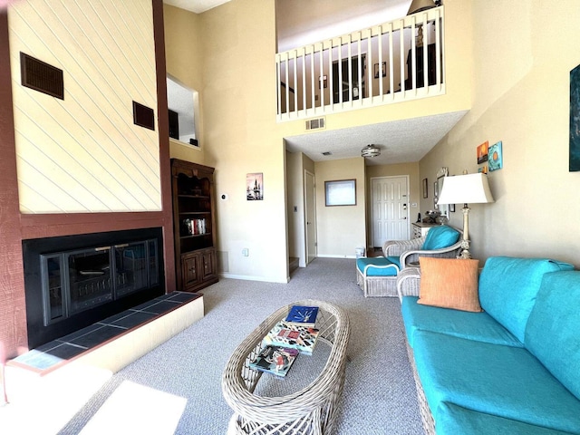 carpeted living room featuring a high ceiling, a tile fireplace, visible vents, and baseboards