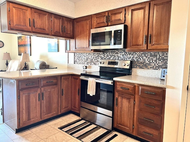 kitchen featuring light countertops, appliances with stainless steel finishes, brown cabinetry, and decorative backsplash