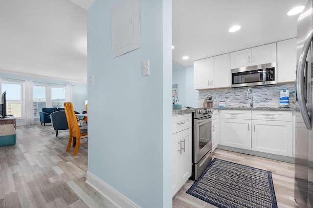 kitchen with appliances with stainless steel finishes, electric panel, light stone countertops, decorative backsplash, and white cabinets