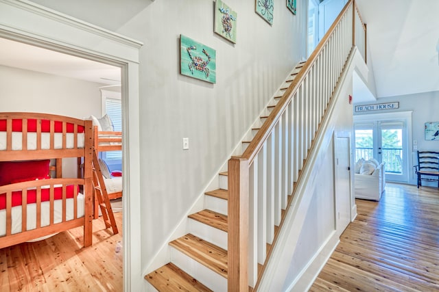 stairs featuring french doors, hardwood / wood-style floors, and a high ceiling