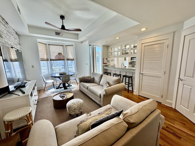 living room featuring a tray ceiling, ceiling fan, and hardwood / wood-style flooring