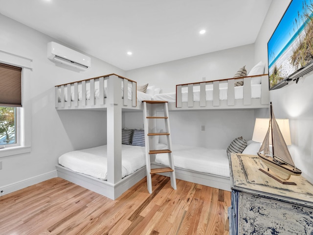 bedroom with light hardwood / wood-style flooring and a wall mounted AC