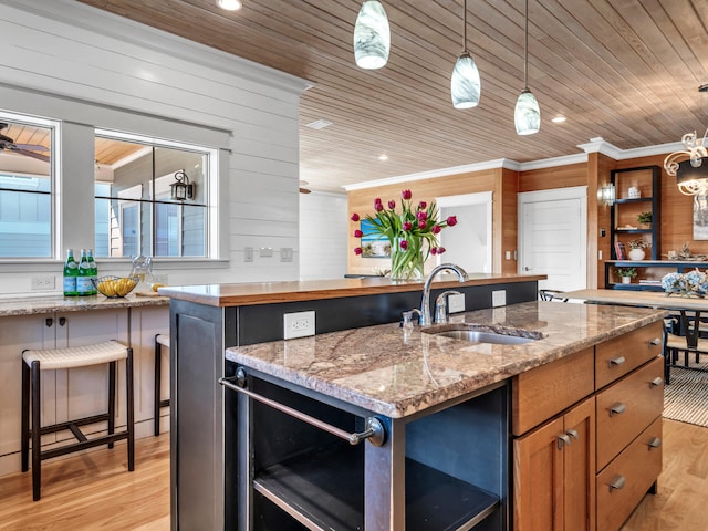 kitchen with sink, a center island with sink, wooden ceiling, pendant lighting, and light stone countertops