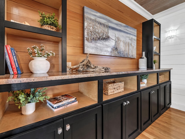 bar with light hardwood / wood-style flooring, ornamental molding, and wood walls