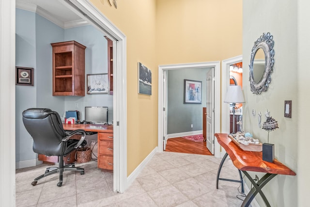 office area featuring light tile patterned floors, crown molding, and built in desk