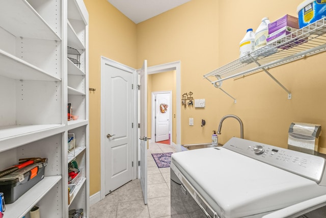 laundry area with light tile patterned flooring, washer / dryer, and sink