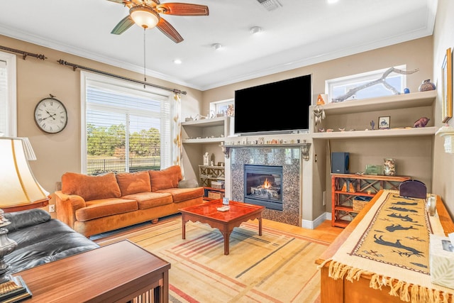 living room with ceiling fan, ornamental molding, and a premium fireplace