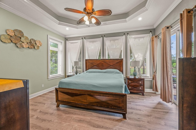 bedroom featuring crown molding, baseboards, a tray ceiling, and wood finished floors
