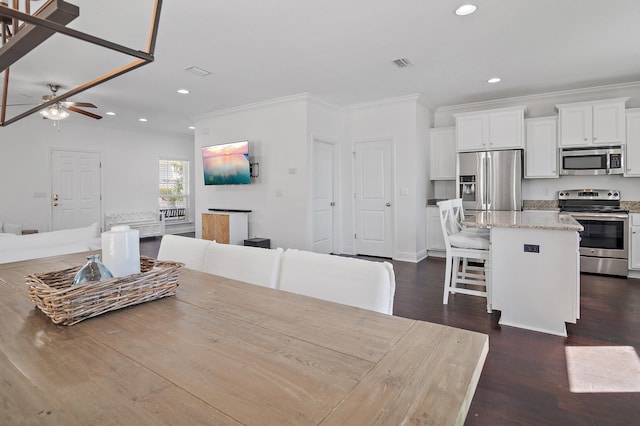 dining room with crown molding, recessed lighting, visible vents, and dark wood finished floors