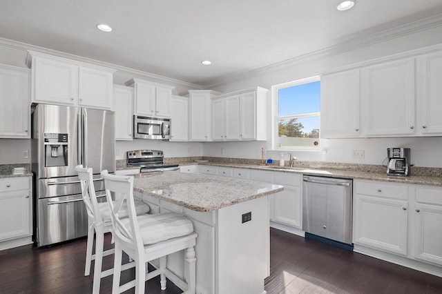 kitchen featuring a center island, dark wood finished floors, crown molding, stainless steel appliances, and white cabinets