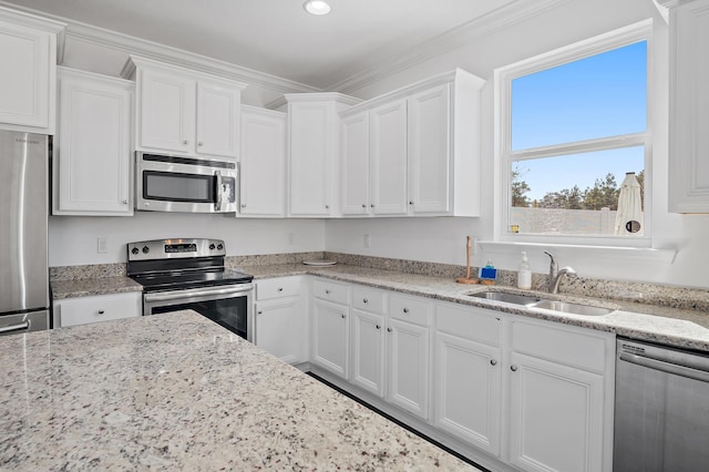 kitchen featuring appliances with stainless steel finishes, crown molding, a sink, and white cabinetry