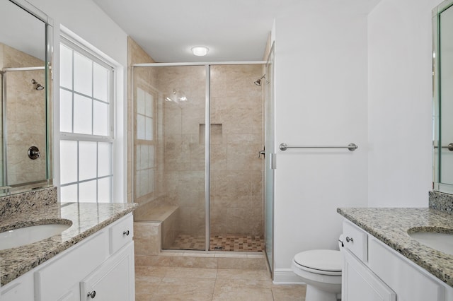 full bath with a stall shower, two vanities, and a sink