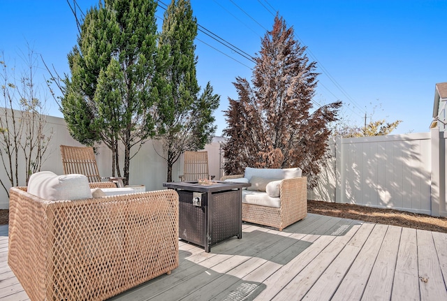 wooden terrace with a fire pit and a fenced backyard