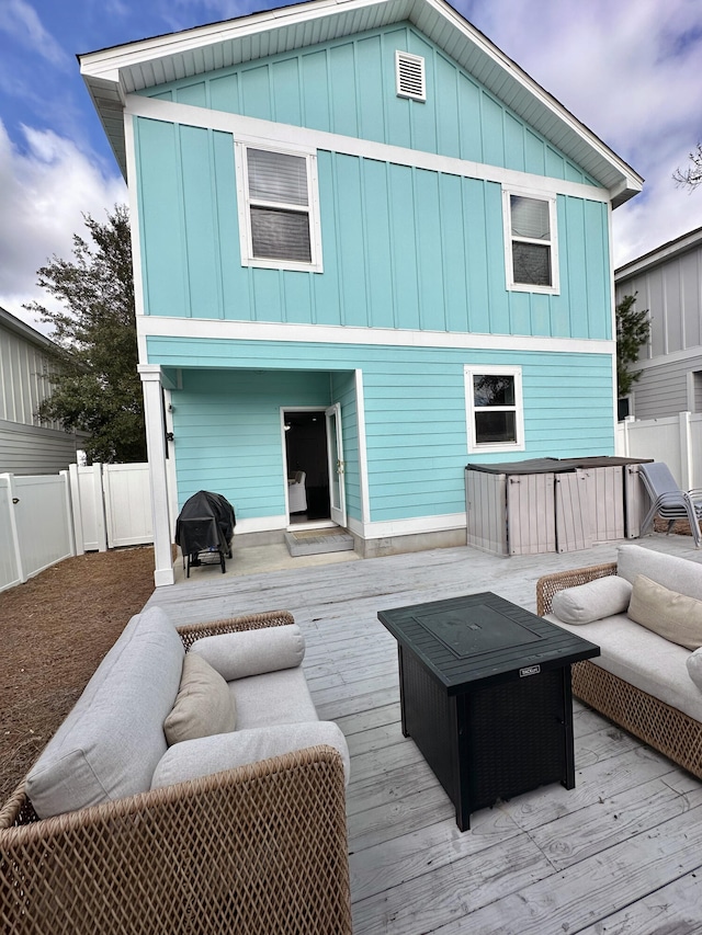 back of property with board and batten siding, a hot tub, a deck, and a fenced backyard