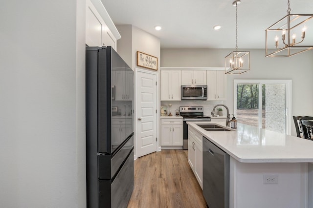 kitchen with sink, an island with sink, white cabinets, and appliances with stainless steel finishes