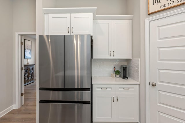 kitchen with white cabinetry, stainless steel fridge, tasteful backsplash, and light wood-type flooring