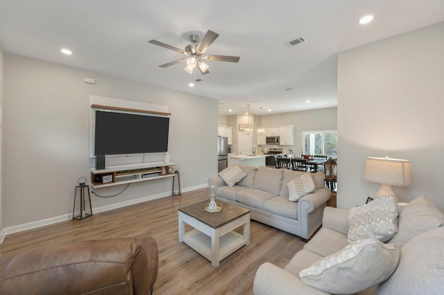 living room featuring sink, ceiling fan, and light hardwood / wood-style flooring