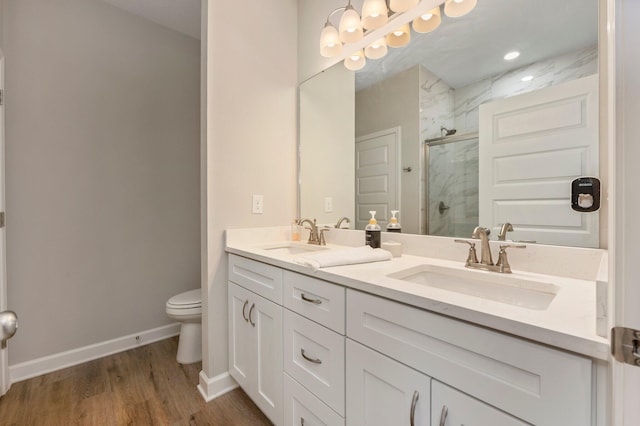 bathroom with an enclosed shower, vanity, hardwood / wood-style flooring, and toilet