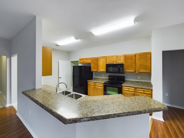 kitchen with sink, black appliances, dark wood-type flooring, and kitchen peninsula