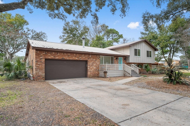 split level home featuring driveway, metal roof, an attached garage, covered porch, and brick siding