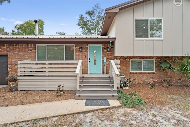 split level home featuring metal roof, brick siding, and board and batten siding