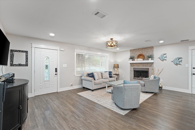 living room featuring a large fireplace, baseboards, visible vents, wood finished floors, and recessed lighting