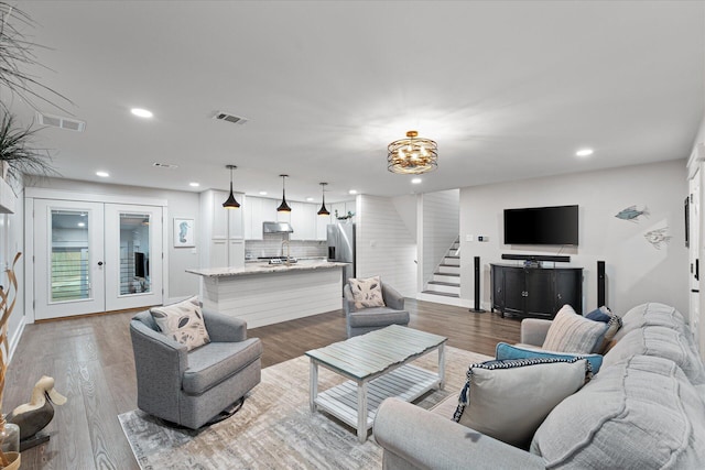 living area with stairway, visible vents, wood finished floors, and french doors