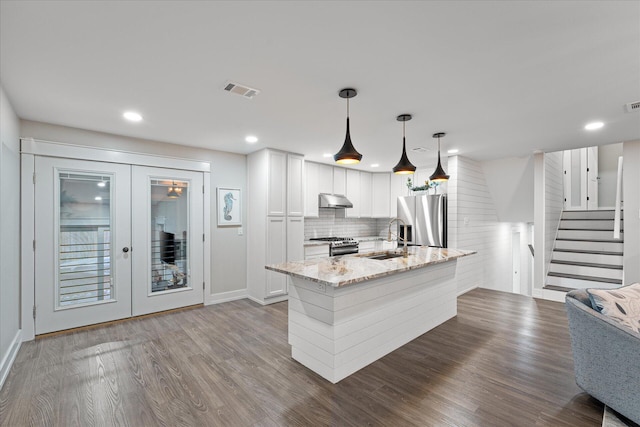 kitchen featuring dark wood finished floors, stainless steel appliances, french doors, under cabinet range hood, and a sink