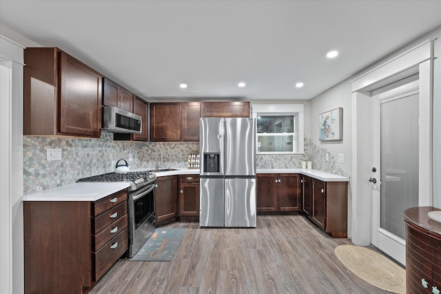 kitchen featuring light wood-type flooring, dark brown cabinetry, tasteful backsplash, and stainless steel appliances