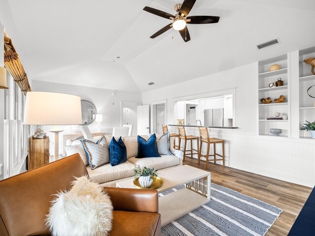 living room with hardwood / wood-style flooring, lofted ceiling, built in features, and ceiling fan