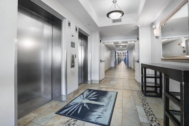 corridor featuring elevator and a tray ceiling