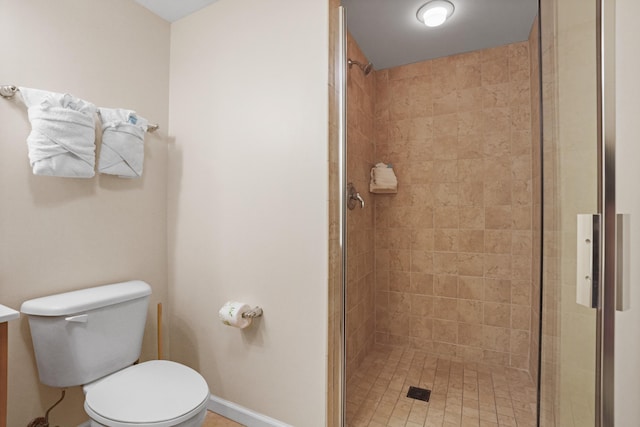 bathroom featuring a shower with door and toilet