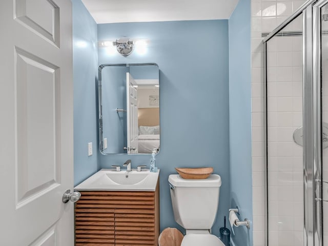 bathroom with vanity, a shower with door, and toilet