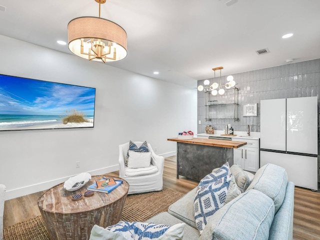 living room featuring wood-type flooring, sink, and an inviting chandelier