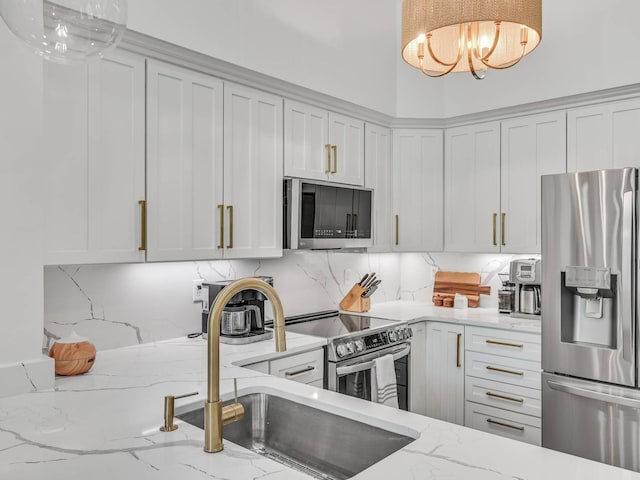 kitchen with pendant lighting, sink, light stone countertops, and appliances with stainless steel finishes