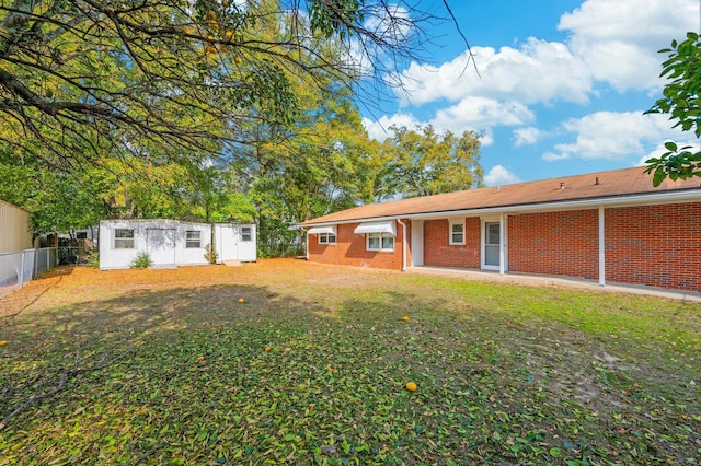 back of house with a yard and an outdoor structure