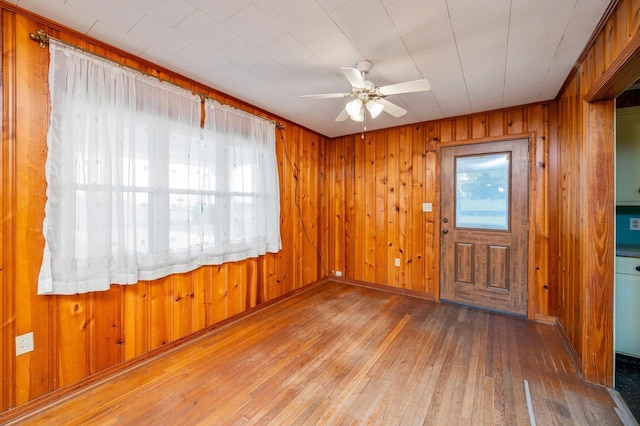 entrance foyer with hardwood / wood-style flooring, plenty of natural light, wooden walls, and ceiling fan