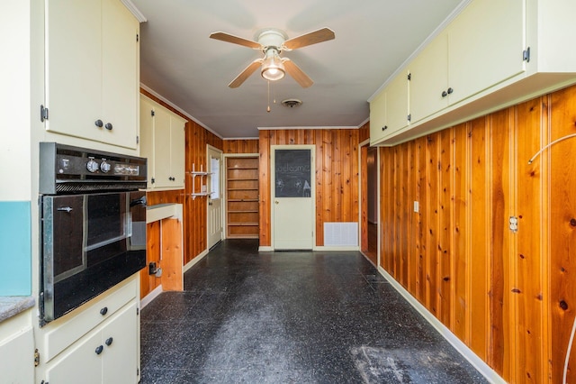 kitchen featuring ornamental molding, oven, ceiling fan, and wood walls